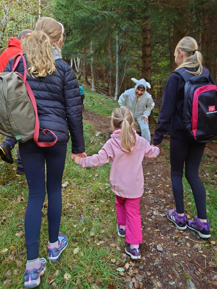 Ein person utkledd som ein hare møter barn i ein skog. - Klikk for stort bilete