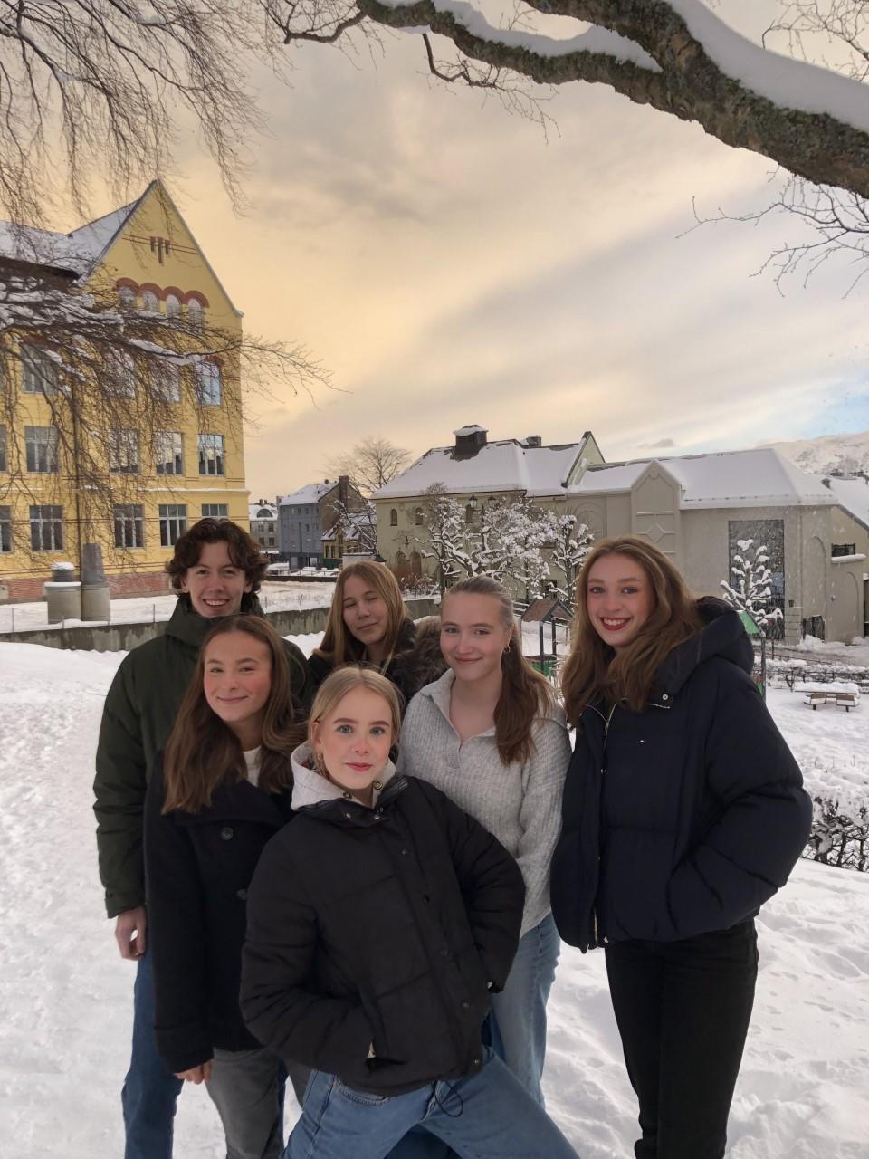 Fem ungdommar i vinterlandskap framfor bygningar i Ålesund.   - Klikk for stort bilete
